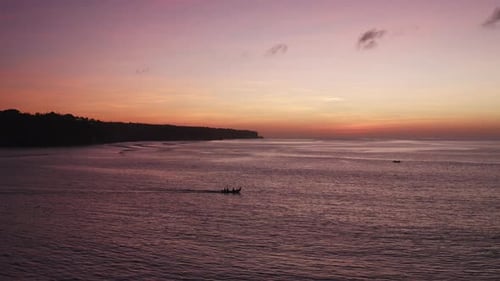 Aerial view over people in a small fishing boat at sunset