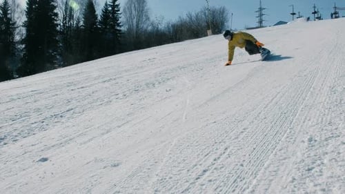 Man geht auf einer Snowboardpiste neben dem Lift den Berg hinunter.