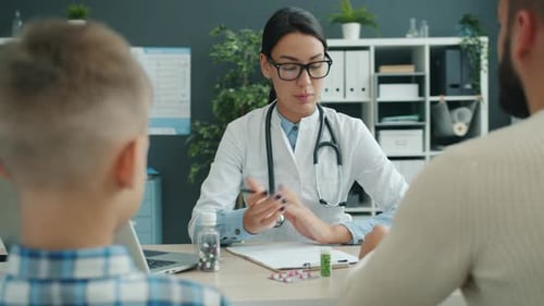 Children's Doctor Talking To Father and Son in Clinic Discussing Child's Health