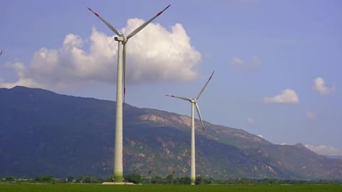Wind Turbines Turning Near Mountains on Sunny Day