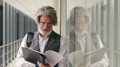 Mature Businessman in Suit Reading in the Airport Terminal