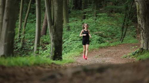 Woman Runs on a Path Through Dense Forest