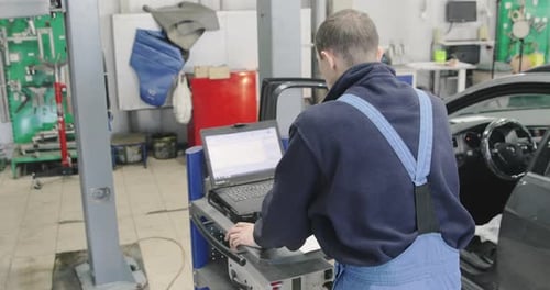 Mechanic Using Laptop for Car Diagnostic in Garage