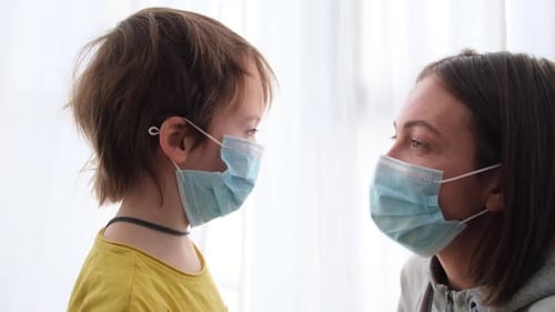 Woman Adjusts Surgical Mask While Talking with Child