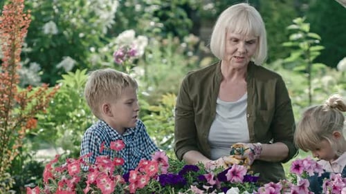 Grandmother and Children Tending Flowers in Garden