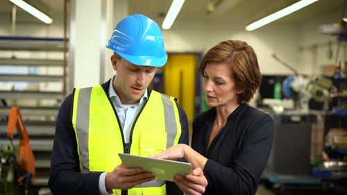 Female manager with digital tablet speaking with coworker in a company