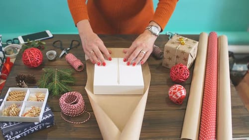 Woman Wrapping Christmas Gift with Brown Paper
