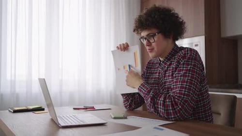 Curly Haired with Glasses Business Man Sitting at Office From Home Desk Looking at Camera and
