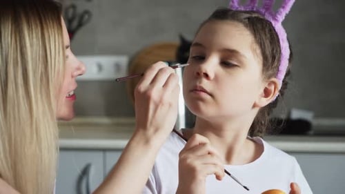 Woman Painting a Child's Face Wearing Bunny Ears
