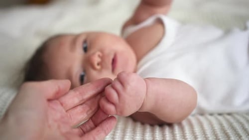 Baby Hand Holding Adult Finger on Bed