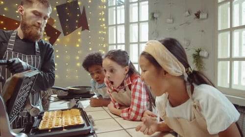 Chef Making Waffles With Eager Children in Kitchen