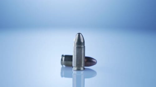 Waffenkontrolle. Munition aus 9-mm-Kugeln, die sich auf einer reflektierenden Oberfläche
drehen