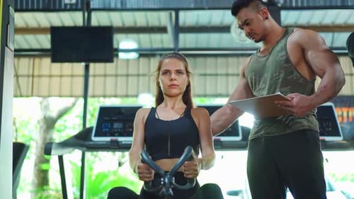 Woman Works Out in Gym with Personal Trainer