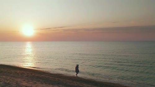 Hermosa escena de una mujer caminando por la playa del océano al atardecer