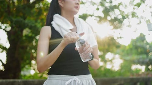 Happy Asian woman running in park on public green background,