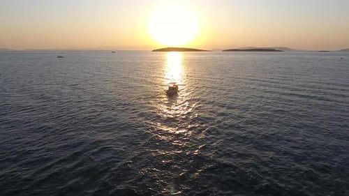 Fishing Boat Sailing at Sunset and Reflection of Evening Sun on the Sea