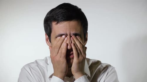 Man Rubbing Eyes and Forehead, Experiencing Headache
