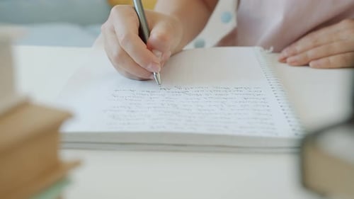 Writing in Notebook on a White Desk
