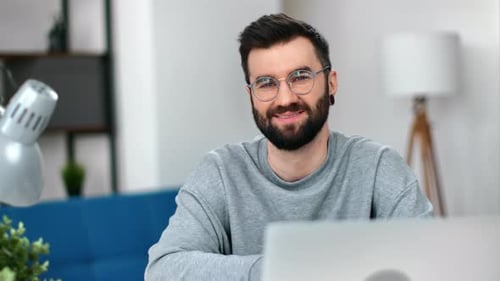 Young Man Smiling in Front of Laptop Indoors