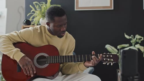 Man Plays Guitar and Sings at Home