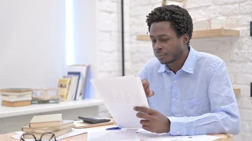 Man Reading Documents at Desk in Office