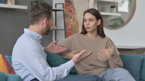 Young Couple Talking Seriously Indoors on Sofa