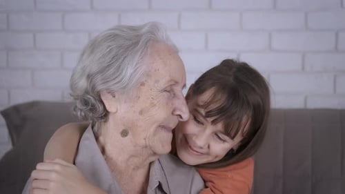 Child Hugs Senior Woman With Love Indoors
