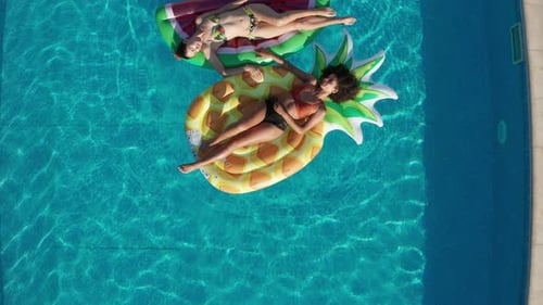 Foto de drone de mulheres relaxadas em carros alegóricos na piscina