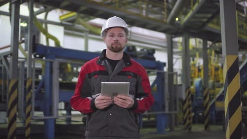 Caucasian Male Engineer Posing in front of Automated Production Line
