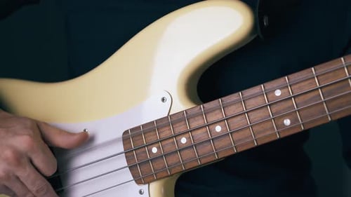 Person Playing a Cream Colored Bass Guitar