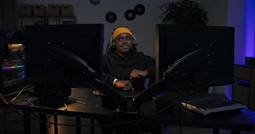 Young Man Gaming with Dual Monitors at Night