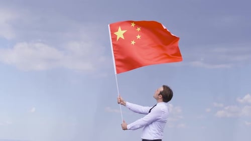 Man Holds Chinese Flag Against Blue Sky