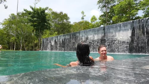 Young Couple Bathing and Relaxing in the Swimming Pool Outdoor on Summer Day