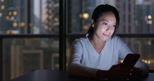 Woman Using Smartphone at Night in City Apartment