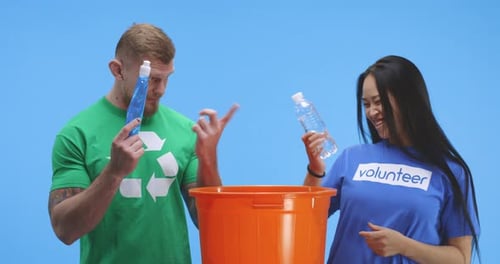 Hombre y mujer conscientes del medio ambiente poniendo una botella en un balde