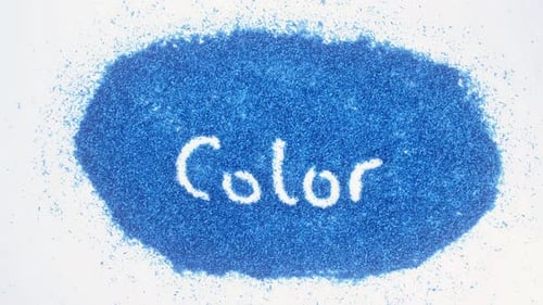 Hand Draws Word Color in Blue Shavings