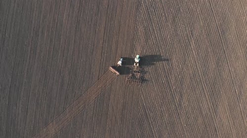 Aerial View of Tractor with Mounted Seeder Performing Direct Seeding of Crops on Plowed Agricultural