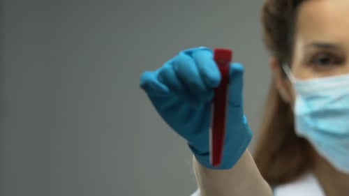 Ärztin hält Reagenzglas mit Blutprobe, Bewusstsein für Infektionskrankheiten