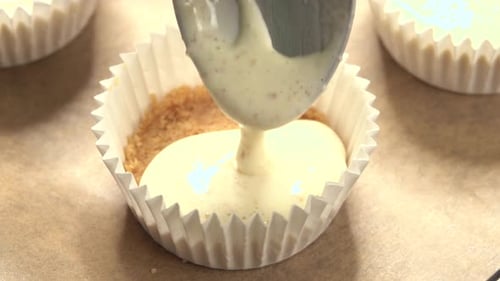 Cupcake pan is filled by pastry chef in close-up view of cookie pan