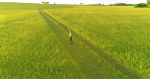 Sporty Child Standing in Green Wheat Field with Raised Hands Up