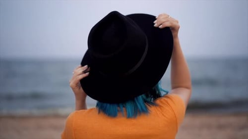 Back Portrait of Unrecognizable Hipster Girl with Blue Hairstyle and Hat on Beach. Unusual Woman