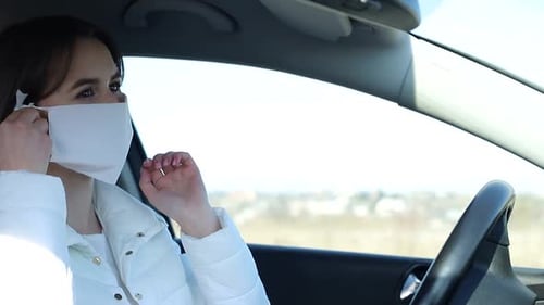 Woman Adjusting Face Mask in Car