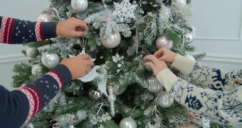 Festive Pair Decorating Christmas Tree with Ornaments
