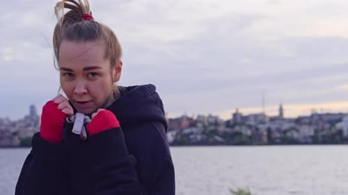 Female Boxer Punches in Red Hand Bandages on the Beach at Sunset