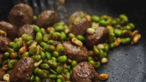 Anonymous person cooking green beans and meatballs
