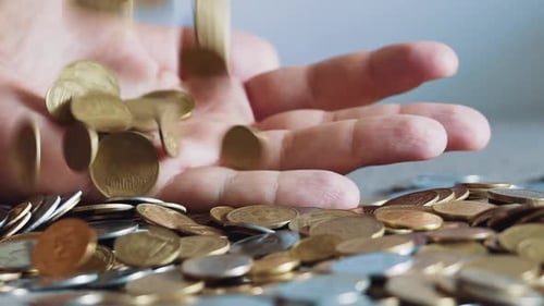 Hand Dropping Shiny Gold and Silver Coins