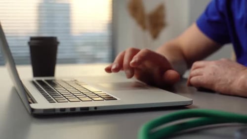 Man Using Laptop at Desk with Stethoscope