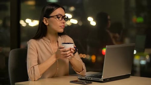 Freelancerin trinkt Kaffee und bearbeitet Projekt auf Laptop