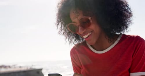 Woman using mobile phone on the beach in sunshine 4k