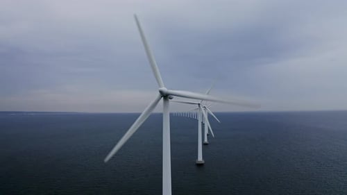 Reihe von Windmühlen und Industriegebiet, umgeben von Meerwasser
